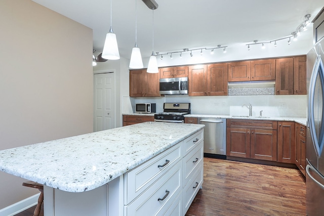 kitchen featuring white cabinets, a center island, stainless steel appliances, pendant lighting, and a sink