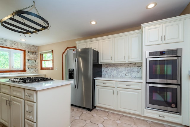 kitchen featuring appliances with stainless steel finishes, decorative backsplash, and white cabinets