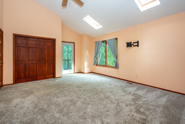 unfurnished bedroom featuring access to outside, a skylight, carpet flooring, and ceiling fan