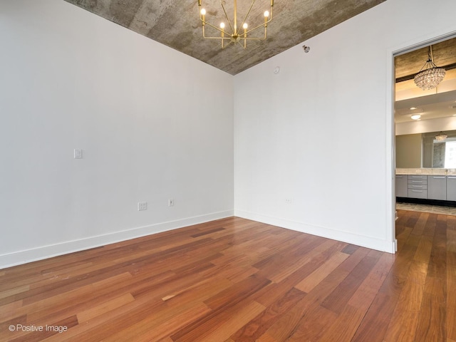 unfurnished room with a chandelier and wood-type flooring