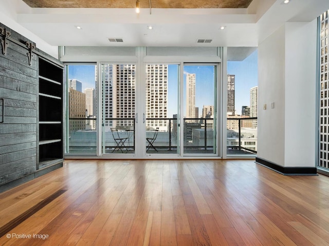 spare room featuring a barn door, built in features, and hardwood / wood-style floors