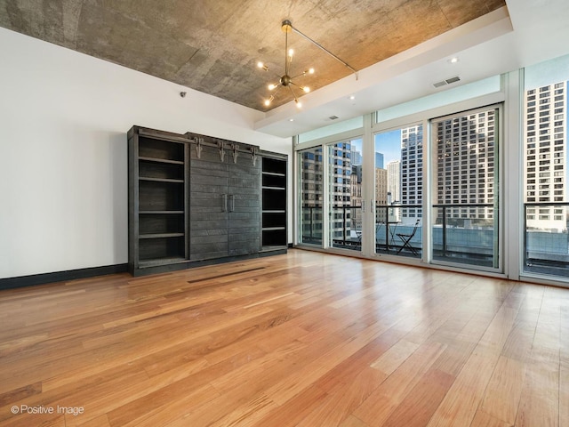 unfurnished room featuring a barn door, light hardwood / wood-style floors, a wealth of natural light, and expansive windows