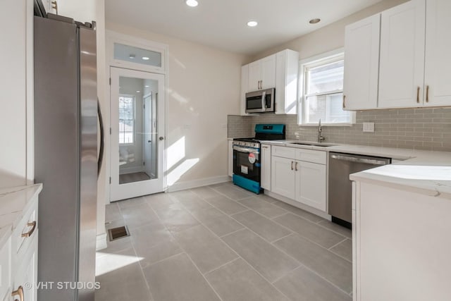 kitchen with appliances with stainless steel finishes, decorative backsplash, sink, and white cabinetry