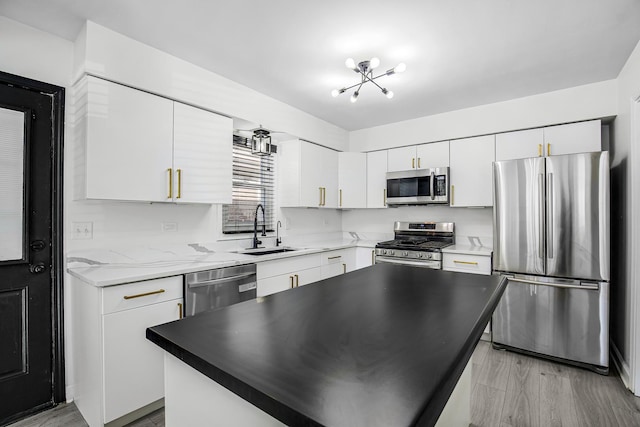 kitchen with white cabinetry, a center island, appliances with stainless steel finishes, and sink