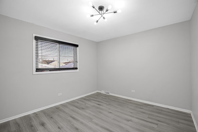 spare room featuring an inviting chandelier and wood-type flooring