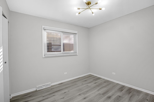 empty room with a notable chandelier and light hardwood / wood-style flooring