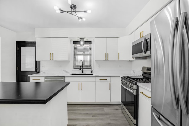 kitchen with appliances with stainless steel finishes, light hardwood / wood-style flooring, a notable chandelier, white cabinets, and sink