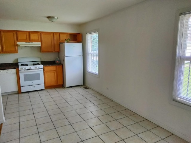 kitchen with white appliances, a healthy amount of sunlight, and light tile patterned floors