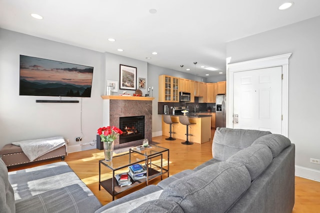 living area featuring a fireplace with flush hearth, recessed lighting, and light wood-style flooring