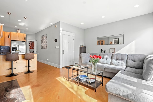 living area featuring light wood-style flooring, baseboards, and recessed lighting