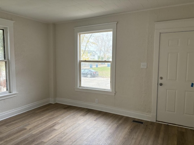 unfurnished room with hardwood / wood-style flooring, plenty of natural light, and ornamental molding