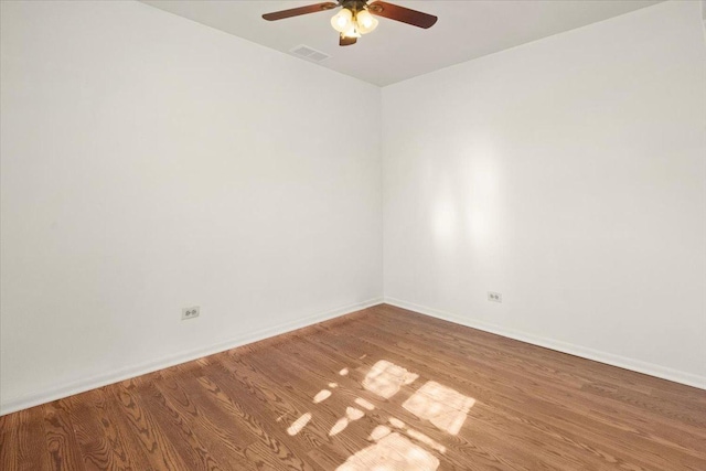 unfurnished room featuring a ceiling fan, visible vents, baseboards, and wood finished floors