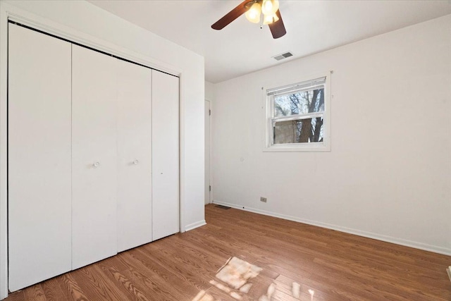 unfurnished bedroom with baseboards, visible vents, ceiling fan, light wood-type flooring, and a closet