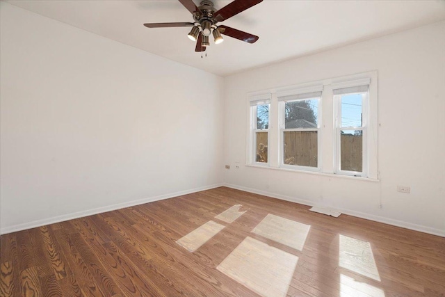 empty room featuring ceiling fan, baseboards, and wood finished floors