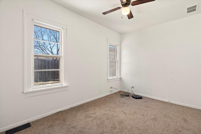 carpeted spare room with visible vents, ceiling fan, and baseboards