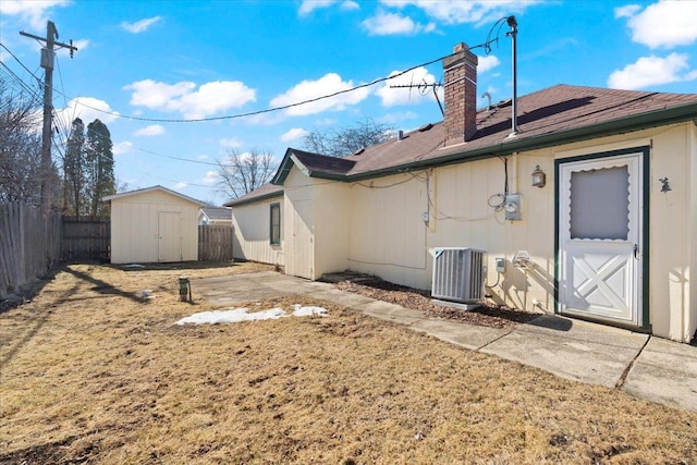 rear view of house with an outbuilding, a fenced backyard, cooling unit, a shed, and a chimney