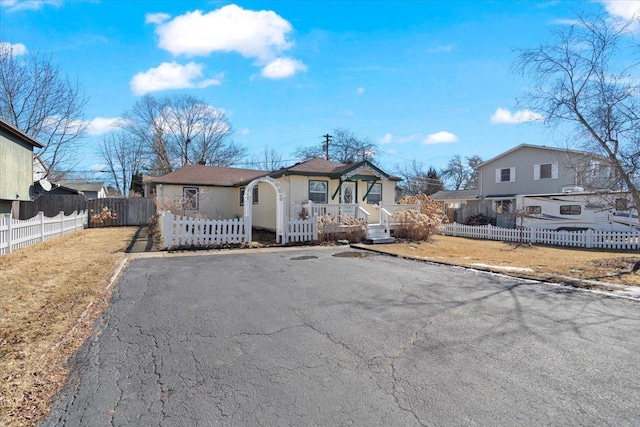 view of front of house with driveway, a fenced front yard, and a residential view