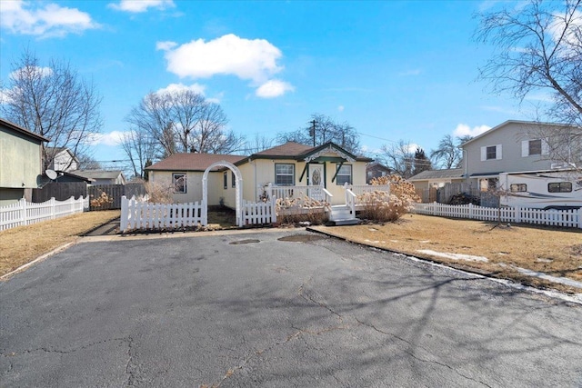 view of front of property with aphalt driveway, a fenced front yard, and a residential view