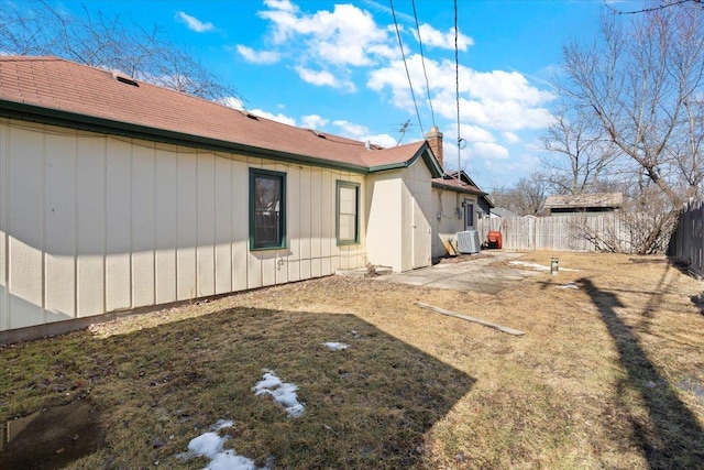 view of property exterior with a patio, a chimney, fence, a yard, and central AC