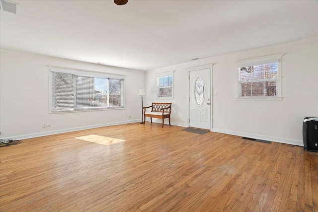 foyer entrance featuring light wood finished floors, plenty of natural light, visible vents, and baseboards