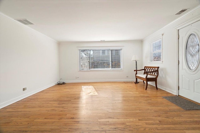 foyer entrance featuring light wood-type flooring, visible vents, and crown molding