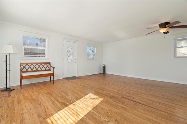 entryway featuring baseboards, crown molding, a ceiling fan, and light wood-style floors