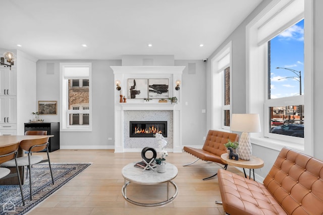 living area with recessed lighting, baseboards, a fireplace, and light wood finished floors