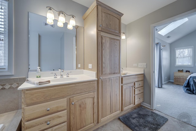 bathroom with tile patterned flooring, vaulted ceiling with skylight, and vanity