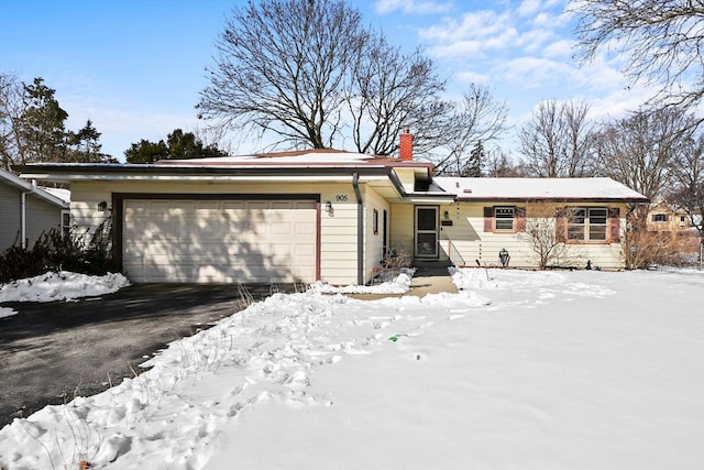 ranch-style home with a chimney, aphalt driveway, and a garage