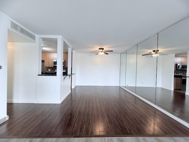 unfurnished living room with dark wood-type flooring and ceiling fan