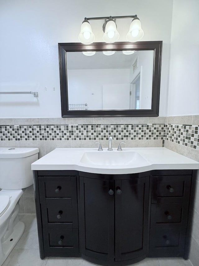 bathroom featuring tile walls, toilet, vanity, and tile patterned flooring