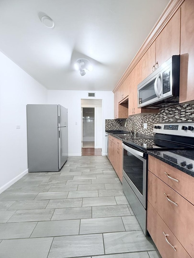 kitchen featuring sink, stainless steel appliances, dark stone counters, and backsplash