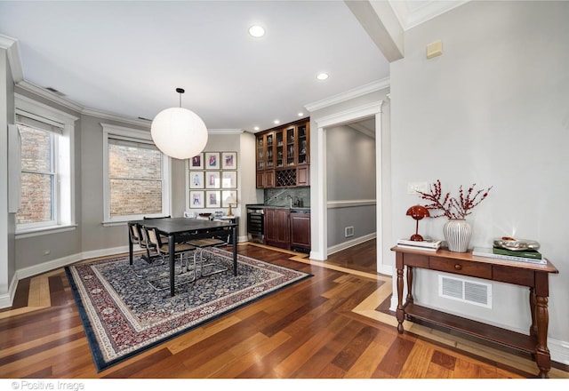 dining area with crown molding, dark wood-style floors, visible vents, and baseboards