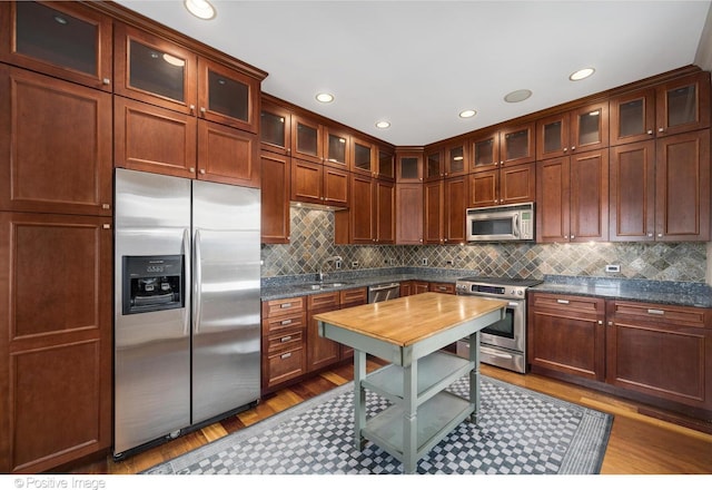 kitchen with glass insert cabinets, dark wood-style floors, backsplash, and appliances with stainless steel finishes