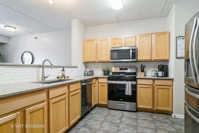 kitchen with light brown cabinetry, appliances with stainless steel finishes, a sink, and tasteful backsplash