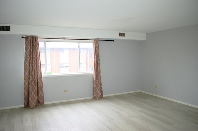 empty room with baseboards, visible vents, and wood finished floors