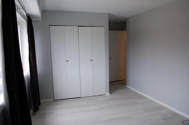 unfurnished bedroom featuring light hardwood / wood-style flooring and a closet