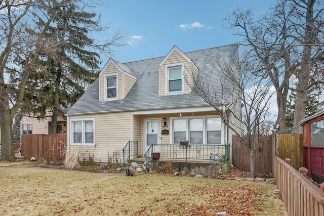 cape cod-style house with a front lawn and fence