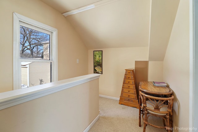 hallway with lofted ceiling, baseboards, light colored carpet, and an upstairs landing