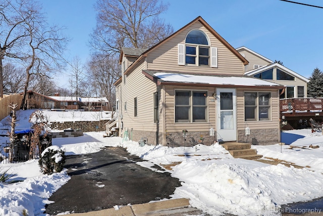 view of front of home featuring stone siding, fence, and a wooden deck