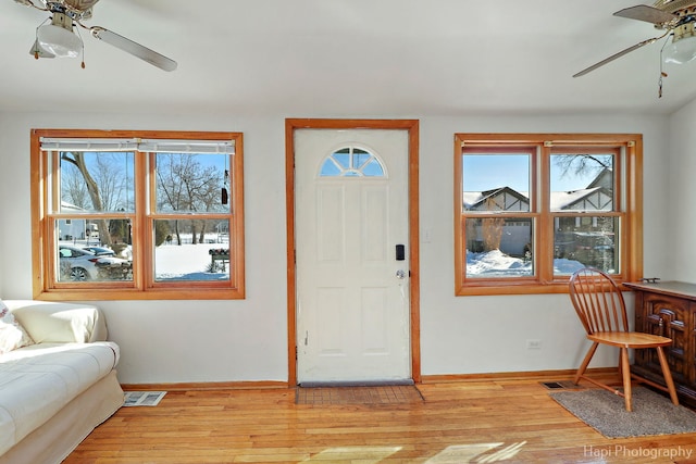 entrance foyer with a ceiling fan, light wood-type flooring, a wealth of natural light, and visible vents