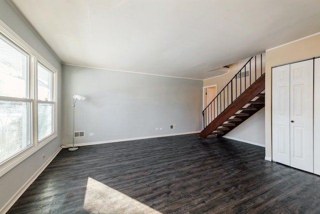 unfurnished living room with dark wood-style flooring, visible vents, stairway, and baseboards