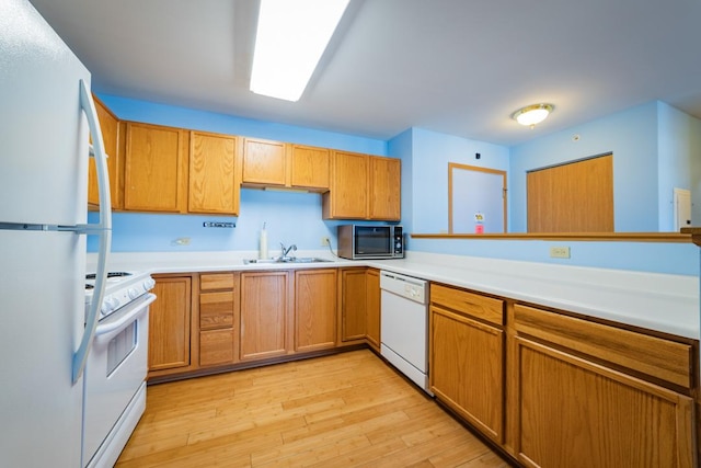 kitchen featuring light wood finished floors, light countertops, brown cabinets, white appliances, and a sink