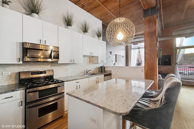 kitchen with stainless steel appliances, a breakfast bar area, decorative light fixtures, and white cabinetry