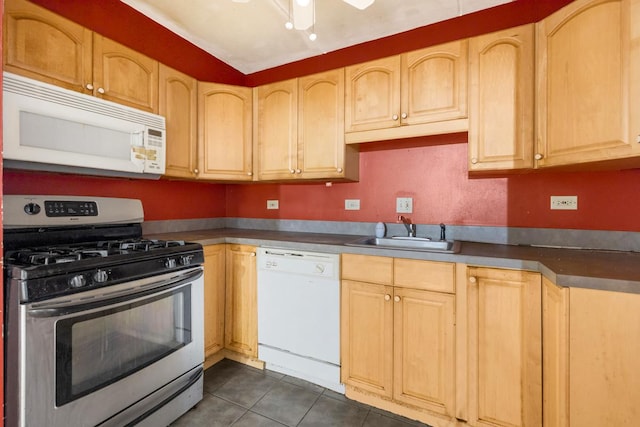 kitchen featuring sink, white appliances, light brown cabinetry, and dark tile patterned floors