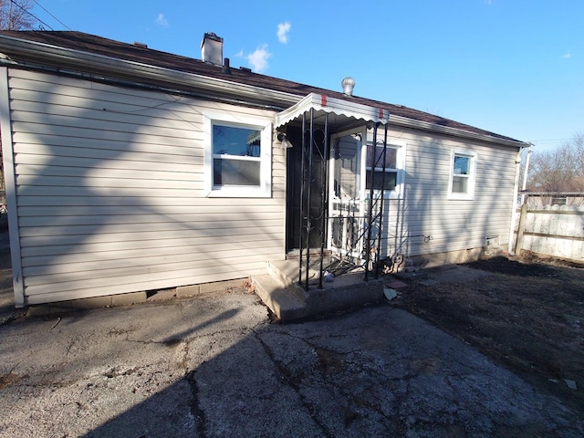 back of property with crawl space, fence, and a chimney