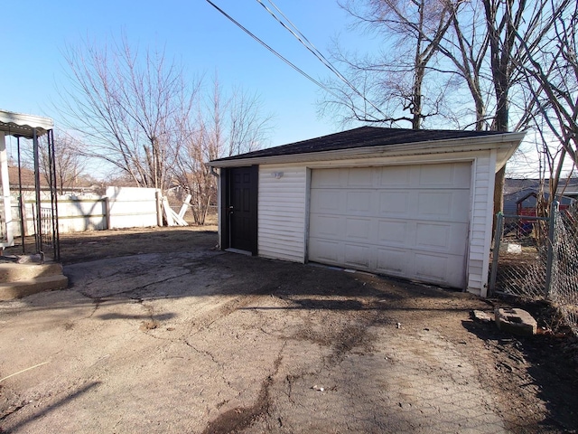 detached garage featuring concrete driveway and fence