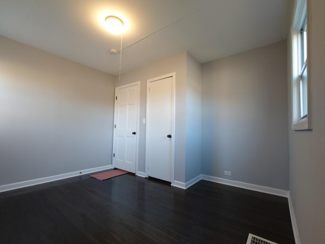 empty room featuring baseboards and dark wood-style flooring