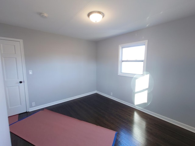 spare room with dark wood-type flooring and baseboards