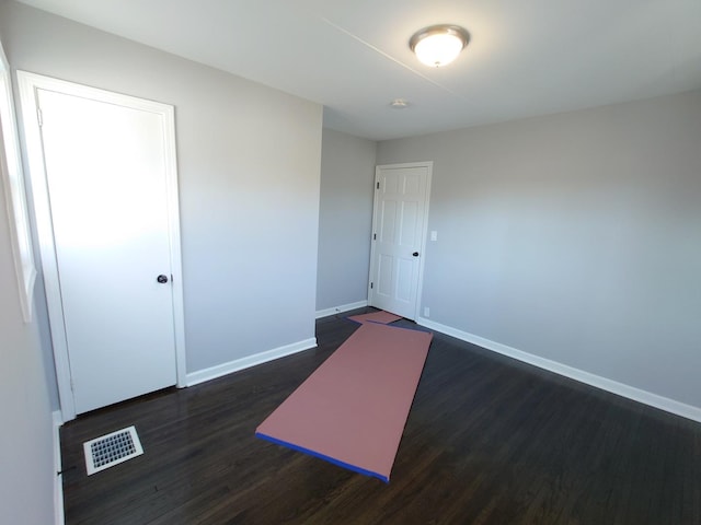 spare room featuring dark wood finished floors, visible vents, and baseboards